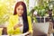 Portrait of beautiful and confident Asian business woman sitting in front of notebook laptop and checking on phone for update