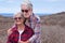 Portrait of beautiful couple of senior travelers in outdoors excursion in arid landscape.  Horizon over sea