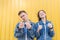 Portrait of a beautiful couple showing thumbs up on a yellow background. Happy couple lifted his fingers up