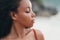 Portrait of beautiful dark skinned girl with closed eyes posing on beach. Sensual afro american model with curly hair