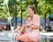 Portrait of beautiful disabled girl in the arms of his mother having fun in fountain of public park at sunny summer day. Child