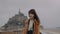 Portrait of beautiful elegant brunette blogger woman smiling at camera at epic Mont Saint Michel island slow motion.