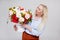 Portrait of beautiful and elegant plus size blonde woman holding box with summer flowers over gray