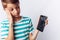 Portrait of a beautiful and emotional boy, in whose hands a broken phone shows surprise, white background, blue t-shirt, advertisi