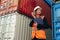 Portrait of beautiful engineer woman with walkie-talkie in white helmet and vest working in container terminal port