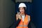 Portrait of beautiful engineer woman with walkie-talkie in white helmet and vest working in container terminal port