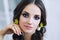 Portrait of beautiful european woman in yellow earings in white apartment, pretty young woman with dark hair in light