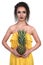 Portrait of a beautiful exsotic fashion girl brunette in the studio in a dress and a woth fruity - a pineapple