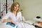 Portrait of a beautiful female cosmetologist in a white coat in a beauty salon sitting pondering near a laser apparat and holding