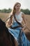 Portrait of a beautiful female cowgirl with shotgun from wild west riding a horse in the outback.