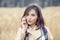 Portrait of a beautiful frustrated woman talking on the mobile phone in a park with a light brown unfocused park nature background