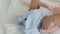 Portrait of beautiful funny little newborn baby of two months lying on a white bed. Mom dresses the baby