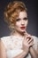 Portrait of a beautiful ginger woman with red lips in the image of the bride.