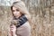 Portrait of a beautiful girl with blue eyes in a grey jacket in the field among trees and tall dry grass, tinted in shades of gray