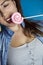 Portrait of a beautiful girl with colorful pink twirl lollipop hard candy on blue background, sweets,sugar  unhealthy