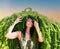 Portrait of a beautiful girl with hair from the green branches of Japanese larch against the blue sky. Hairstyle from green