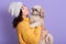 Portrait of beautiful girl keeping pretty Pekingese and wants kissing him, side view of female looks at her favorite puppy, lady