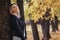 Portrait of a beautiful girl leaning on a tree trunk, a young woman walks in the autumn park on nature