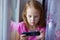 Portrait of a beautiful girl with a mobile phone. Cute girl watching cartoon on the mobile phone.