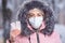 Portrait of a beautiful girl in a pink jacket in a medical protective mask in holding pills in her hands for colds and flu. Winter