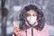 Portrait of a beautiful girl in a pink jacket in a medical protective mask in holding yellow pills in her hands for colds and flu