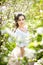 Portrait of beautiful girl posing outdoor with flowers of the cherry trees in blossom during a bright spring day