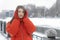 Portrait of beautiful girl in red warm jacket and knitted mittens in winter outside. Trendy youth winter clothing