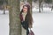 Portrait of beautiful girl in the snow hiding behind a tree.