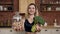 Portrait of a beautiful girl standing at the kitchen table holding in right hand a glass bowl with bagels in left hand