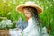 Portrait of a beautiful girl in a straw hat with a gray rabbit in a field with flowers