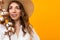 Portrait of a beautiful girl with a summer hat with a sprig of cotton on a yellow background