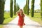 Portrait of beautiful girl in Umbria. Young fashion woman walking in cypresses lane on sunny day. Travels in Italy