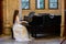 Portrait of a beautiful girl wearing white wedding dress at the piano playing