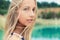 Portrait of beautiful girls with full lips and blond hair stands near the lake