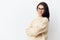 portrait of a beautiful, happy, neat woman in a beige turtleneck sweater and black-rimmed glasses, standing on a light