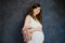 Portrait of beautiful happy pregnant caucasian girl on dark background. Maternity, pregnancy concept.