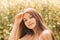 Portrait of a beautiful and happy young girl with long hair against the background of rapeseed flowers. Youth and nature