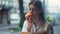 Portrait of beautiful healthy young woman eating an apple and attentively reading a book in a cafe on the urban