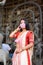 Portrait of beautiful Indian girl standing in front of Durga Idol wearing traditional Indian saree, gold jewellery, bangles and