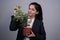 Portrait of a beautiful Indian young business woman in a business suit, holding a green indoor flower in her hand, smiling,