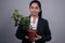 Portrait of a beautiful Indian young business woman in a business suit, holding a green indoor flower in her hand, smiling,