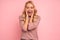 Portrait of beautiful joyous woman screaming and gesturing as winner isolated over pink background in studio