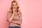 Portrait of beautiful joyous woman smiling and looking upward at copyspace isolated over pink background in studio