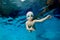 Portrait of a beautiful little boy in a Christmas hat and glasses in a pool underwater. Baby learns to dive. Swimming