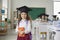 Portrait of a beautiful little curly elementary school graduate girl wearing an academic hat.