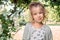 Portrait of beautiful little girl 4-7 years old with blue-green emerald eyes in flowering spring summer park on natural background