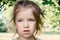 Portrait of beautiful little girl 4-7 years old with blue-green emerald eyes in flowering spring summer park on natural background