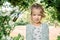 Portrait of beautiful little girl 4-7 years old with blue-green emerald eyes in flowering spring summer park on natural background