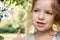 Portrait of beautiful little girl 4-7 years old with blue-green emerald eyes in flowering spring summer park on natural background