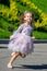 Portrait of a beautiful little girl with luxurious long hair outdoors. Running child